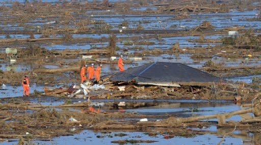 Rescue workers are seen checking through the remains of a tsunami-wrecked house in Miyagi prefecture