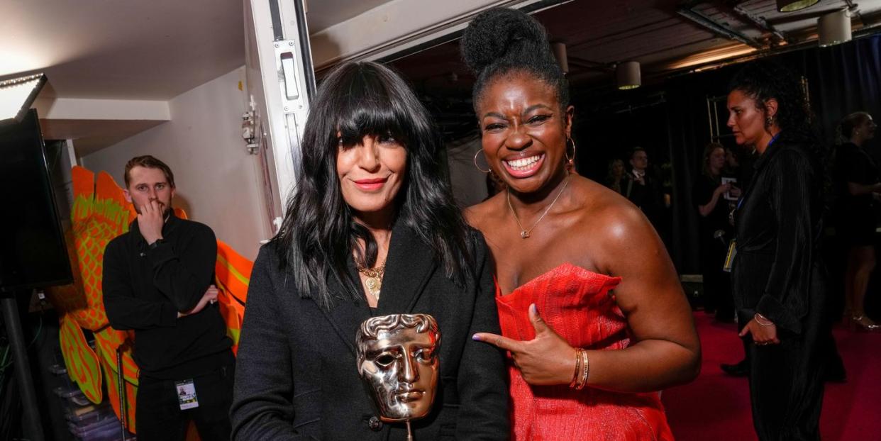 claudia winkleman holds a bafta trophy as clara amfo points at her and smiles