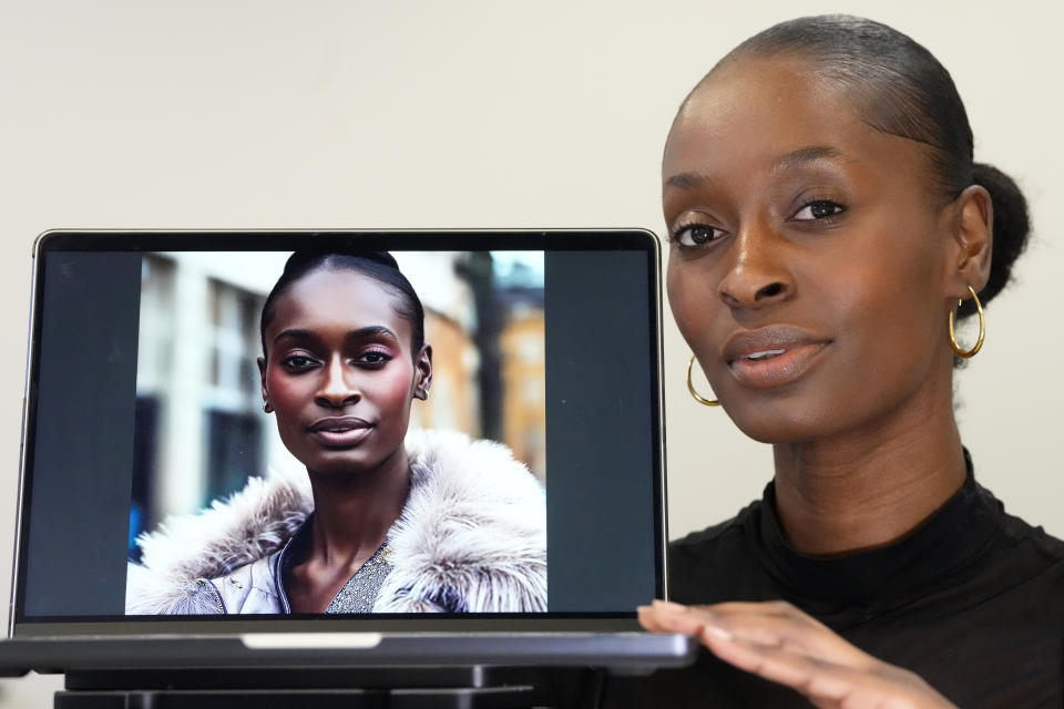 Fashion model Alexsandrah poses with a computer showing an AI generated image of her, in London, Friday, March 29, 2024. The use of computer-generated supermodels has complicated implications for diversity. Although AI modeling agencies -- some of them Black-owned -- can render models of all races, genders and sizes at the click of a finger, real models of color who have historically faced higher barriers to entry may be put out of work. (AP Photo/Kirsty Wigglesworth)