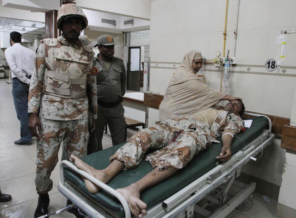 A Pakistani woman comforts a security officer injured in an attack on Wednesday, Jan. 29, 2014, in Karachi, Pakistan. Police said several members of the country's security forces have been killed in separate attacks in the southern city of Karachi. (AP Photo/Fareed Khan)