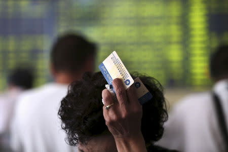 Investors are seen in front of an electronic board showing stock information at a brokerage house in Nantong, Jiangsu province, China, July 28, 2015. REUTERS/Stringer