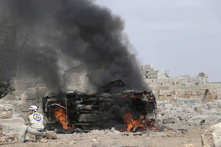 A civil defense member tries to put out the flames on a burning military vehicle at a base controlled by rebel fighters from the Ahrar al-Sham Movement, that was targeted by what activists said were Russian airstrikes at Hass ancient cemeteries in the southern countryside of Idlib, Syria October 1, 2015. REUTERS/Khalil Ashawi