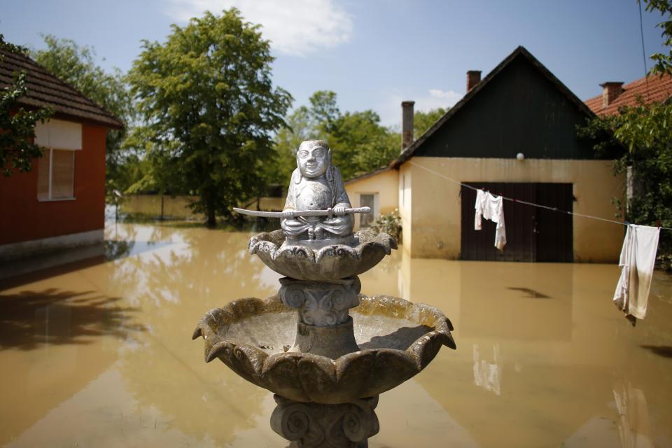 Religious statue is seen in front of a flooded house in Obrenovac