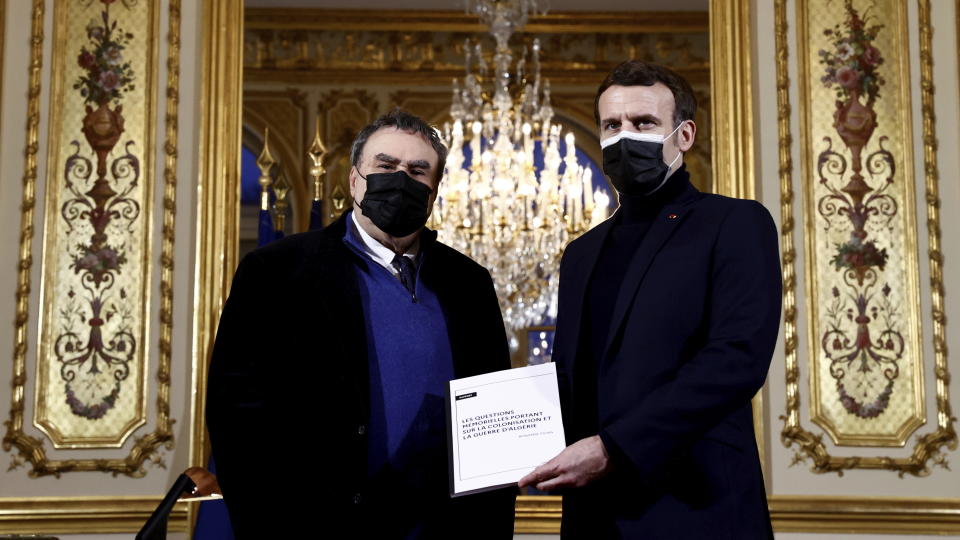 FILE - In this Jan.20, 2021 file photo French President Emmanuel Macron, right, gets a report from French historian Benjamin Stora as he receives the report on the memory of the colonization and the Algerian war at the Elysee Palace in Paris. President Emmanuel Macron has met with four grandchildren of an Algerian independence fighter to tell them that Ali Boumendjel had been tortured and assassinated at the hands of French soldiers in 1957, taking another step in his effort at reconciling France with its colonial past and offering anew an outstretched hand to Algeria, France's crown jewel in 132 years of occupation. (Christian Hartmann/Pool via AP)