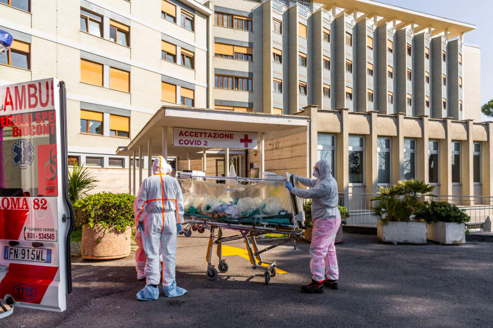 A coronavirus patient arrives on a stretcher at the Columbus Covid Hospital, after being transferred by medical workers in protective white suits from the Gemelli Hospital, in Rome
