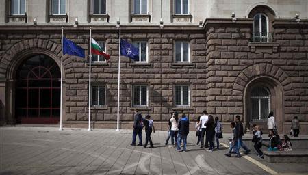 People walk past the EU, Bulgarian and NATO (L-R) flags after a flag-raising ceremony as part of celebrations of the 10th anniversary of Bulgaria joining NATO, in front of the Presidency in Sofia April 4, 2014. REUTERS/Pierre Marsaut