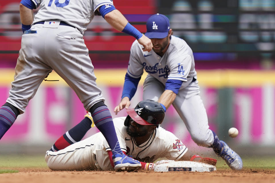 Atlanta Braves' Abraham Almonte, bottom, advances to second base as the ball gets away from Los Angeles Dodgers left fielder Chris Taylor, top right, after a Ehire Adrianza base hit in the sixth inning of a baseball game Sunday, June 6, 2021, in Atlanta. (AP Photo/Brynn Anderson)