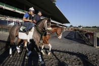 FILE - In this June 4, 2013, file photo, Preakness winner Oxbow, left, enters the track for a light workout at Belmont Park in Elmont, N.Y. Trainer D. Wayne Lukas is at rear. The order of the Triple Crown races could be different this year. “If you go from a mile-and-a-half and start dropping back, it’s going to change a lot,” said Lukas, winner of 14 Triple Crown races. “It’ll change how you train, it’ll change the type of horse that will end up in the Derby. It’ll be a very, very significant change.” (AP Photo/Mark Lennihan, File)