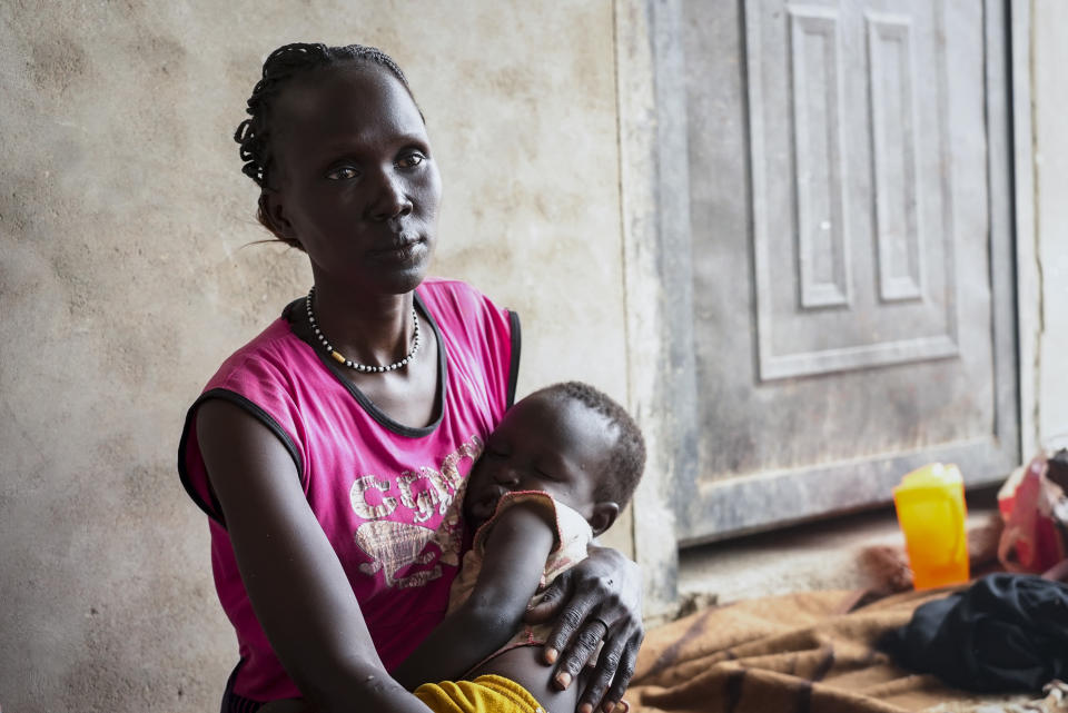 South Sudanese Alwel Ngok, 31, who fled from Sudan, sits holding her son in a church in Renk, South Sudan Tuesday, May 16, 2023. Tens of thousands of South Sudanese are flocking home from neighboring Sudan, which erupted in violence last month. (AP Photo/Sam Mednick)