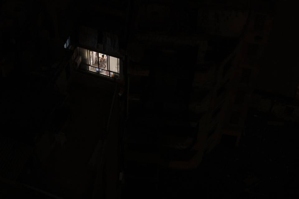 A person walks around their lit apartment during a power outage in Beirut, Lebanon Monday, July 6, 2020. The government in highly indebted Lebanon is in talks with the International Monetary Fund to secure financial assistance. But the talks have been bogged down by political divisions. Poverty and unemployment have been rising, only to be compounded by the economic restrictions imposed in effort to try to curb the spread of the coronavirus. (AP Photo/Hassan Ammar)