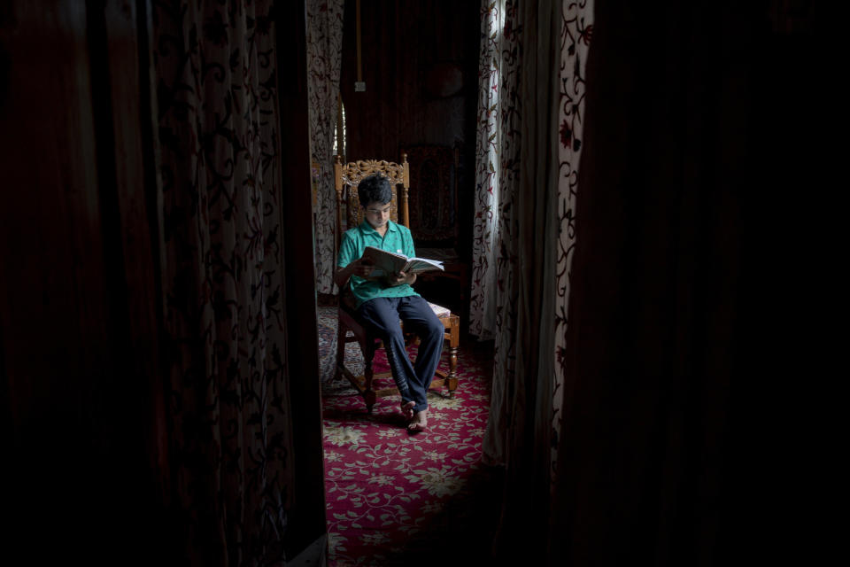 Mohsin Shafi holds a book and sits for a photograph inside their houseboat on the Dal Lake in Srinagar, Indian controlled Kashmir, Wednesday, July 22, 2020. Schools in the disputed region reopened after six months in late February, after a strict lockdown that began in August 2019, when India scrapped the region’s semi-autonomous status. In March schools were shut again because of the coronavirus pandemic. "We are not able to keep up with lessons online and we miss our regular school," he said. (AP Photo/Dar Yasin)