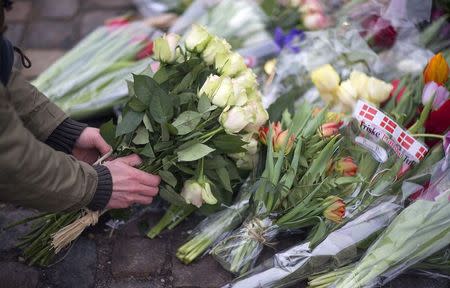 A man places flowers close to the scene of a cafe shooting in Oesterbroin in Copenhagen, February 15, 2015. REUTERS/Hannibal Hanschke