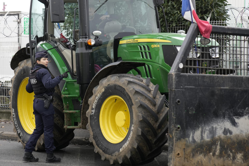 A police officer talks to a farmer outside the Rungis international market, which supplies the capital and surrounding region with much of its fresh food, Wednesday, Jan. 31, 2024 in Rungis, south of Paris. French farmers maintained their protests on major roads around Paris and across the country on Wednesday as police was deployed to protect the capital, its airports and an international market. (AP Photo/Christophe Ena)