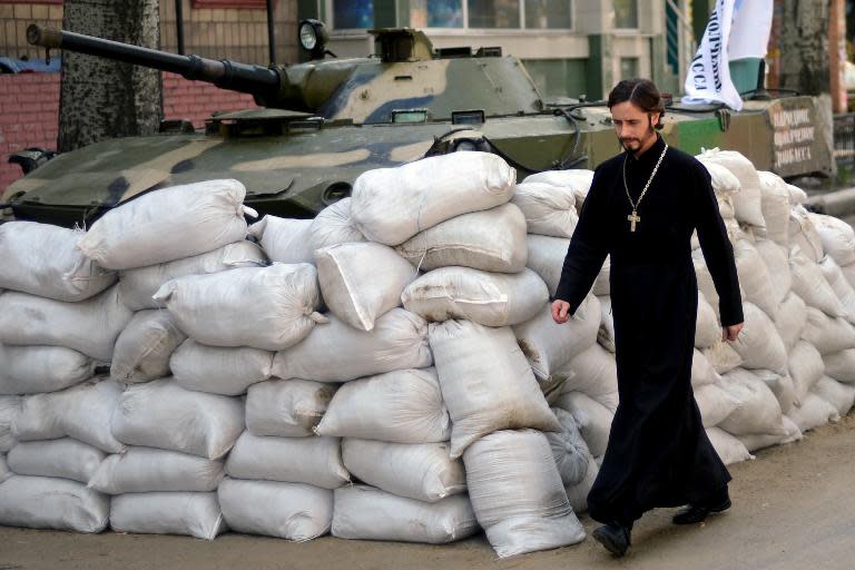 An Orthodox priest walks past a barricade outside the security service (SBU) regional building seized by separatists in the eastern Ukrainian city of Slavyansk on April 23, 2014