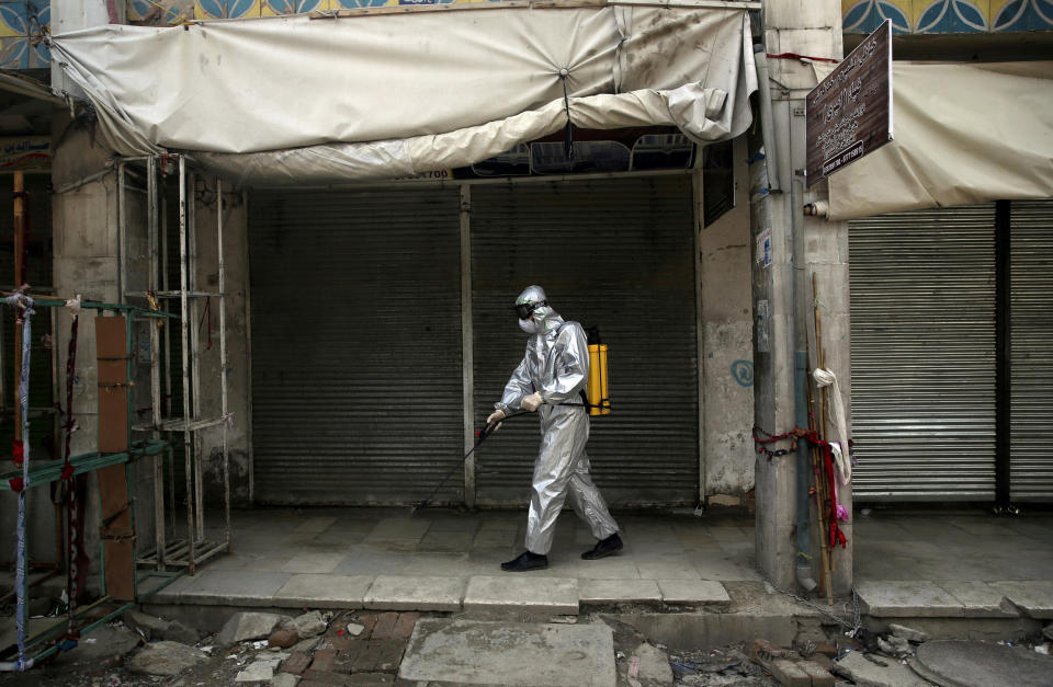 Image: Volunteers spray disinfectant on storefronts  (Rahmat Gul / AP)