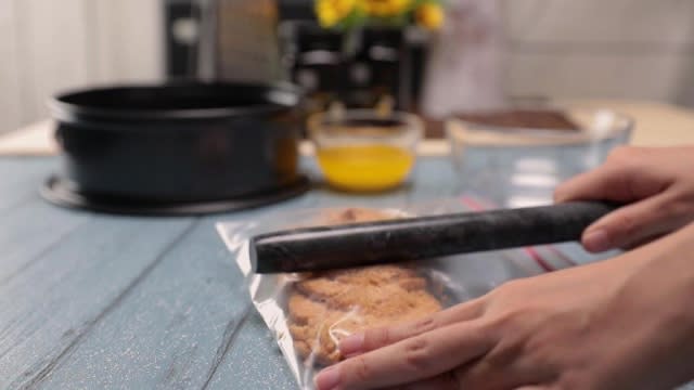 Crushing digestive biscuits in a ziplock bag into crumbs with a rolling pin