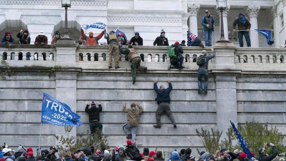 Insurrectionists scale a wall of the U.S. Capitol on Jan. 6, 2021. A man allegedly involved in the riots was arrested Thursday outside the home of former President Barack Obama. (Photo by Jose Luis Magana, AP, File)