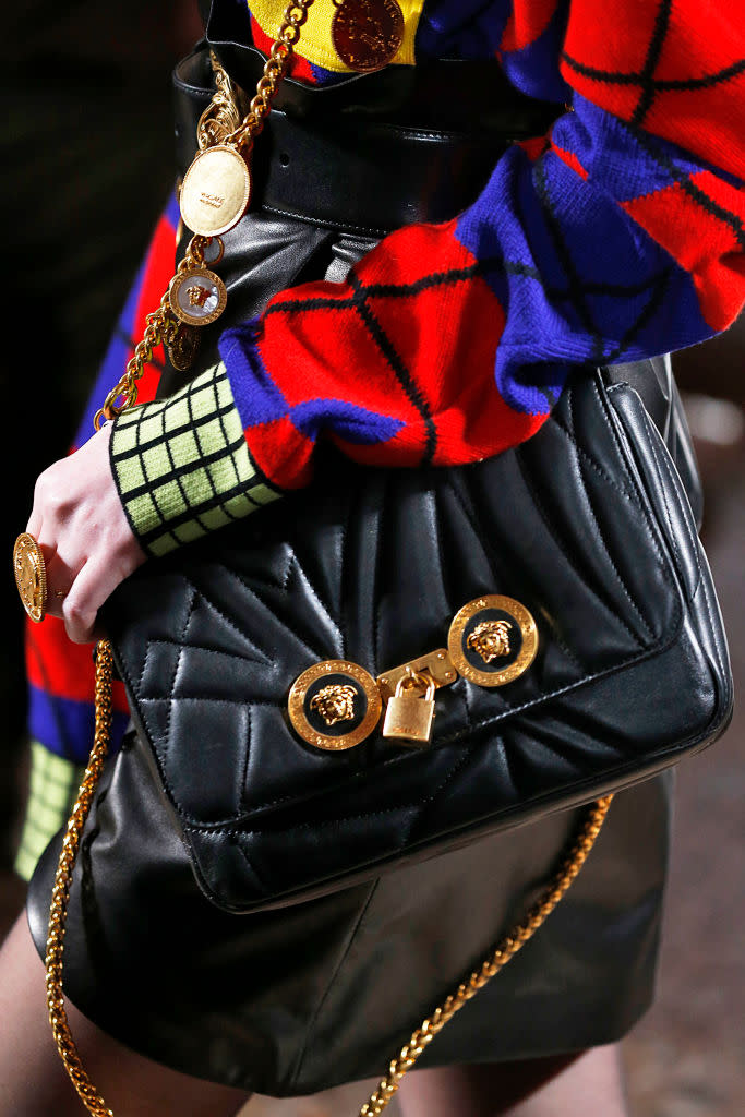 <p>A model carries a black, quilted, gold-chain bag from the Versace FW18 show. (Photo: Getty Images) </p>