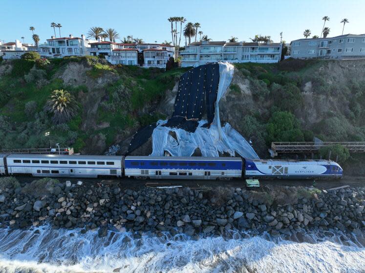 San Clemente, CA - March 08: An aerial view of Amtrak Pacific Surfliner resuming service while passing through the repaired tracks and barrier wall construction at Mariposa Point in San Clemente Friday, March 8, 2024. Rail service is on a limited basis. The reopening of the line this week marked the first time in more than a month that passengers have been able to hop aboard Amtrak's Pacific Surfliner and ride through the coastal swath between Orange County and San Diego. Construction continues on the barrier wall, which will be 10 to 15 feet high and 192 feet long. A series of powerful winter storms saturated the hillside adjacent to the tracks, causing it to slide and crumble, and forcing officials to halt train service for weeks. (Allen J. Schaben / Los Angeles Times)