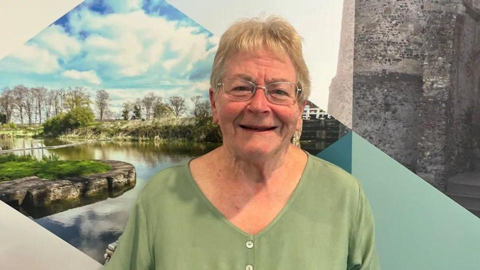 Sue Dillon from the shoulders up, with a colourful wall behind her