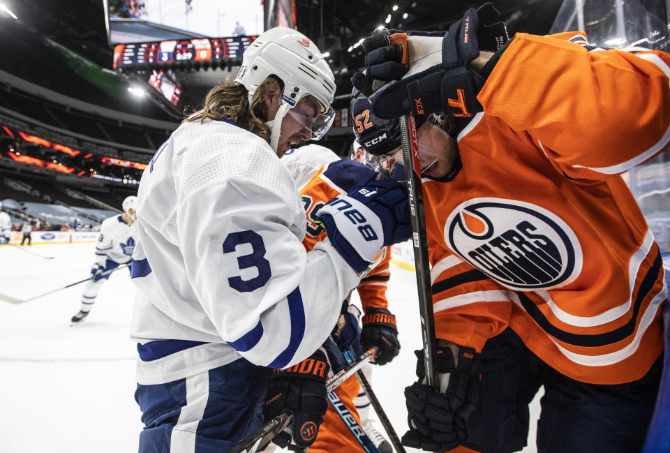 Edmonton Oilers' Patrick Russell (52) and Toronto Maple Leafs' Justin Holl (3) battle for the puck during the second period of an NHL game in Edmonton, Alberta, on Saturday, Feb. 27, 2021. (Jason Franson/The Canadian Press via AP)