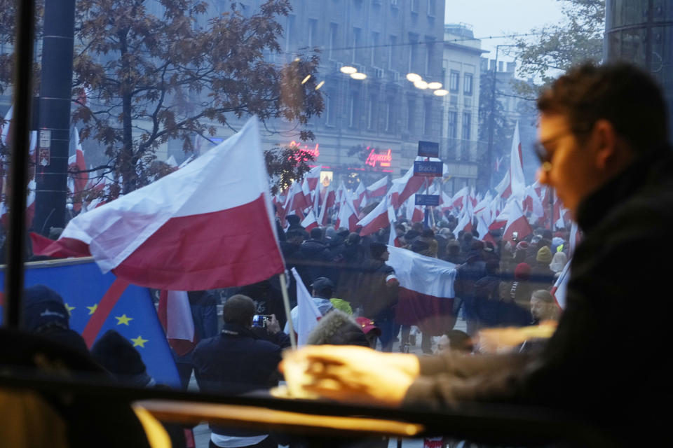 A man sits inside a cafeteria as people outside take part in a yearly march on Poland's Independence Day holiday in Warsaw, Poland, on Saturday, Nov. 11, 2023. The Independence Day holiday celebrates the restoration of Poland's national sovereignty in 1918, at the end of World War I and after 123 years of foreign rule. (AP Photo/Czarek Sokolowski)