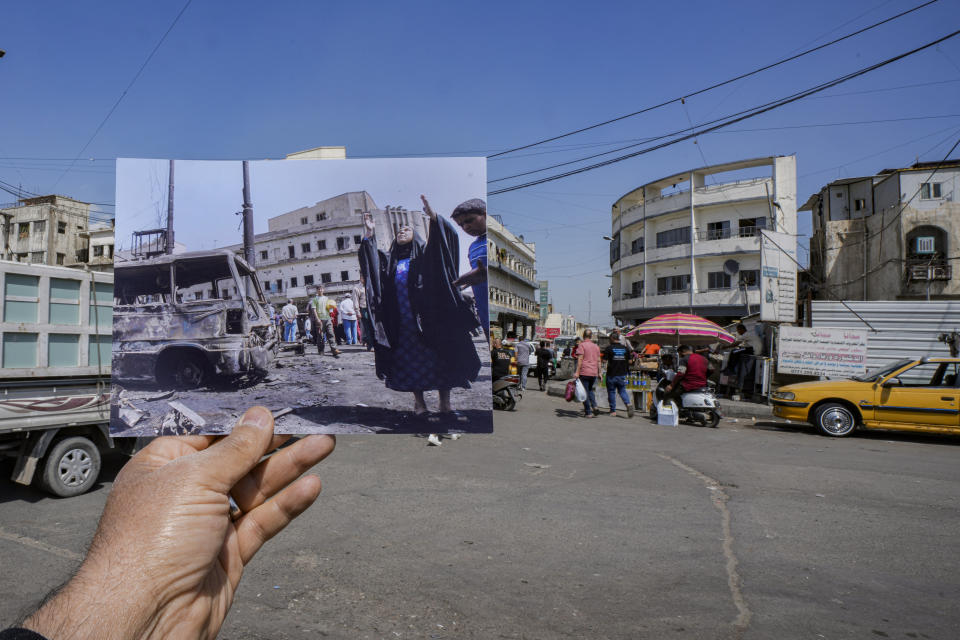 A photograph of a woman reacting at the scene of a car bomb which killed over a hundred people at the Sadriyah market in Baghdad, Iraq, Thursday, April 19, 2007, is inserted into the scene at the same location on Monday, March 20, 2023. 20 years after the U.S. led invasion on Iraq and subsequent war. (AP Photo/Hadi Mizban)