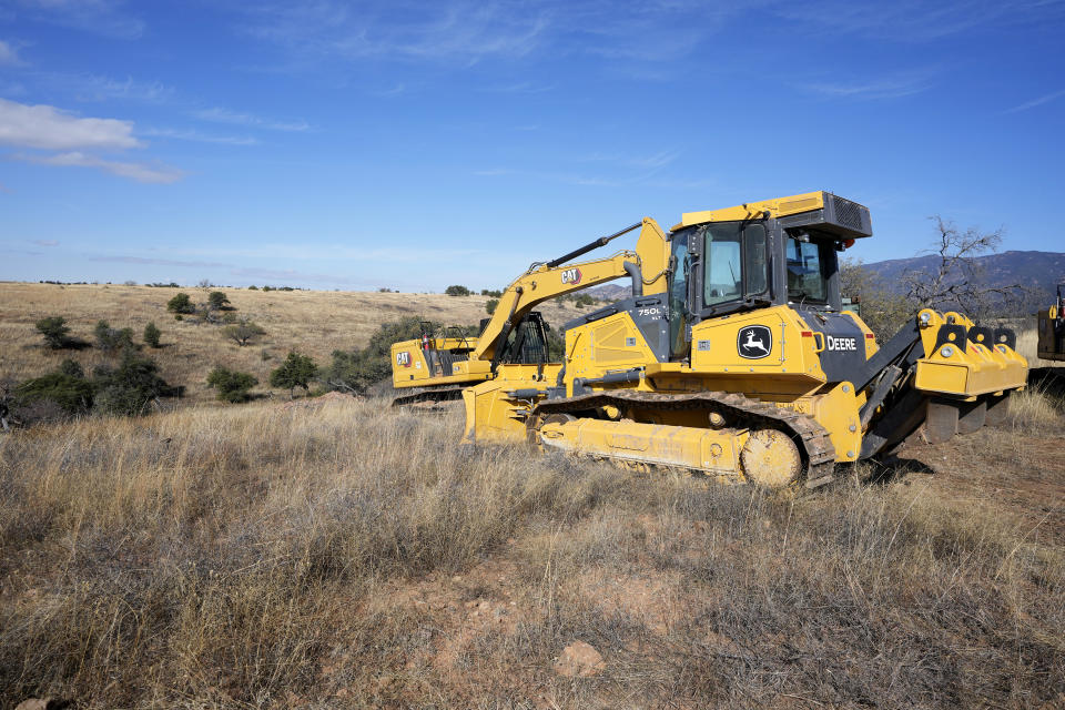 Idle construction equipment park along the border where shipping containers create a wall between the United States and Mexico in San Rafael Valley, Ariz., Thursday, Dec. 8, 2022. Work crews are steadily erecting hundreds of double-stacked shipping containers along the rugged east end of Arizona’s boundary with Mexico as Republican Gov. Doug Ducey makes a bold show of border enforcement even as he prepares to step aside next month for Democratic Governor-elect Katie Hobbs. (AP Photo/Ross D. Franklin)