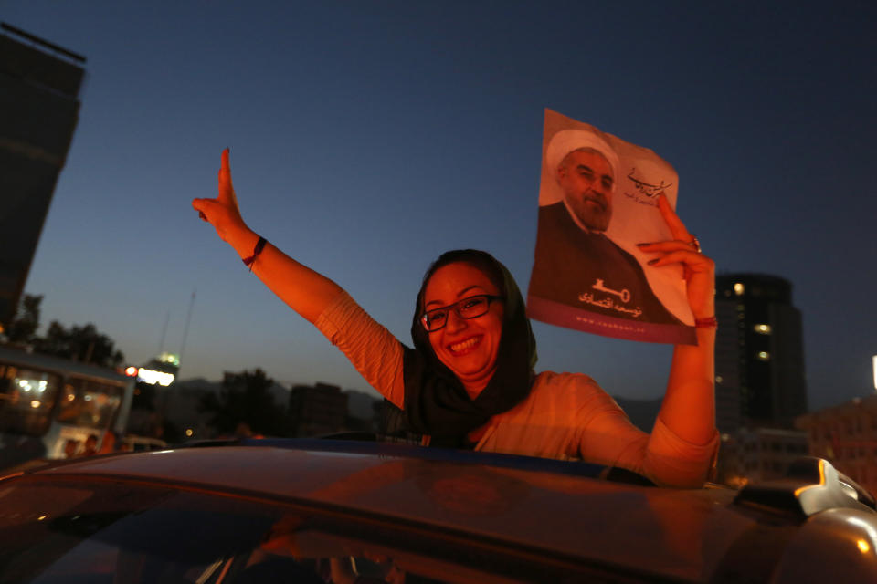 An Iranian woman celebrates the victory of moderate presidential candidate Hassan Rouhani (portrait) in the presidential elections at Vanak Square, in northern Tehran, on June 15, 2013. (ATTA KENARE/AFP/Getty Images)