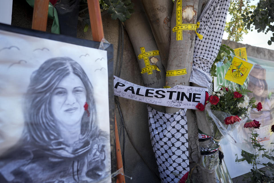 FILE - Yellow tape marks bullet holes on a tree and a portrait and flowers create a makeshift memorial at the site where Palestinian-American Al-Jazeera journalist Shireen Abu Akleh was shot and killed in the West Bank city of Jenin, May 19, 2022. The Palestinian Authority said Thursday, May 26, 2022, its investigation into the shooting death of Al Jazeera journalist Shireen Abu Akleh proves she was deliberately killed by Israeli forces. Israel is likely to reject the findings as biased and unfounded. (AP Photo/Majdi Mohammed, File)