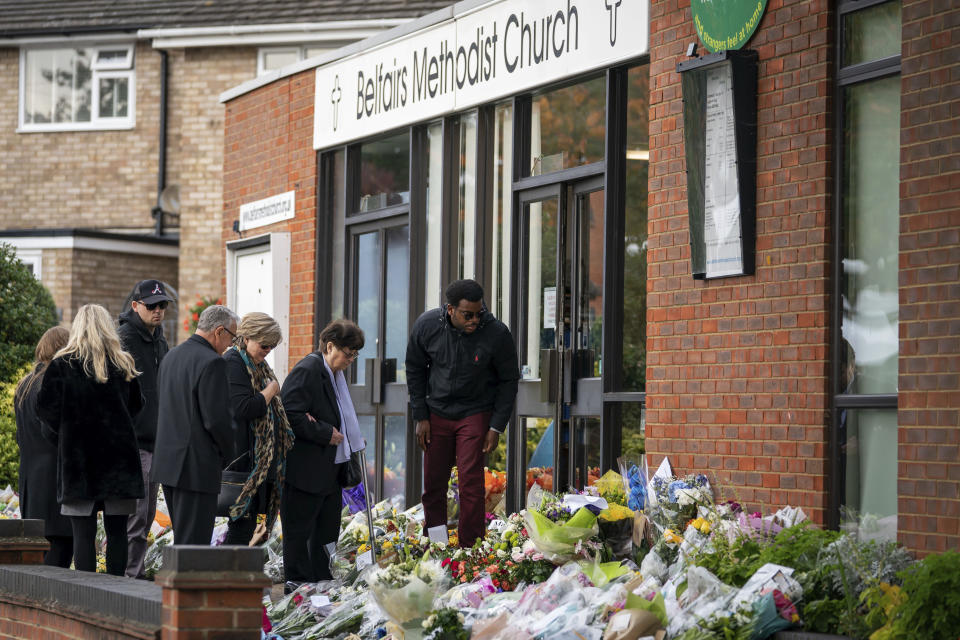 The Rev Clifford Newman of Belfairs Methodist Church, fourth left, talks with Julia Amess, the widow of Conservative MP David Amess, arrives with friends and family members to view flowers and tributes left for her late husband at Belfairs Methodist Church, where he died after being stabbed several times during a constituency surgery on Friday, in Leigh-on-Sea, Essex, England, Monday, Oct. 18, 2021. A 25-year-old British man with Somali heritage, Ali Harbi Ali, is being held under the Terrorism Act on suspicion of murder in David Amess' killing. Police say the suspect appears to have acted alone and may have had a “motivation linked to Islamist extremism.” (Aaron Chown/PA via AP)