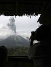 Villagers take pictures of Mount Sinabung erupting from a food stall at Simpang Empat village in Karo district, Indonesia's north Sumatra province, November 5, 2013. A volcano erupted for the third time in as many months on the western Indonesian island of Sumatra, forcing hundreds of villagers to evacuate, officials said. Mount Sinabung spewed a 7-km (4.3-mile) column of ash into the air on Sunday, prompting authorities to impose a 3-km evacuation radius. REUTERS/Roni Bintang (INDONESIA - Tags: ENVIRONMENT DISASTER)