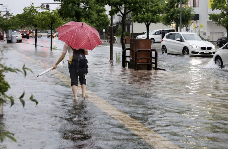 A person walks in a flooded street near a railway station in Saga