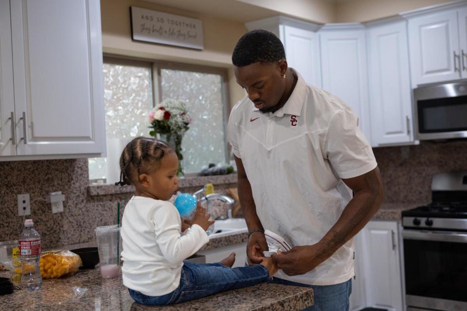 Solomon Byrd puts shoes on his 2-year-old son, Messiah.