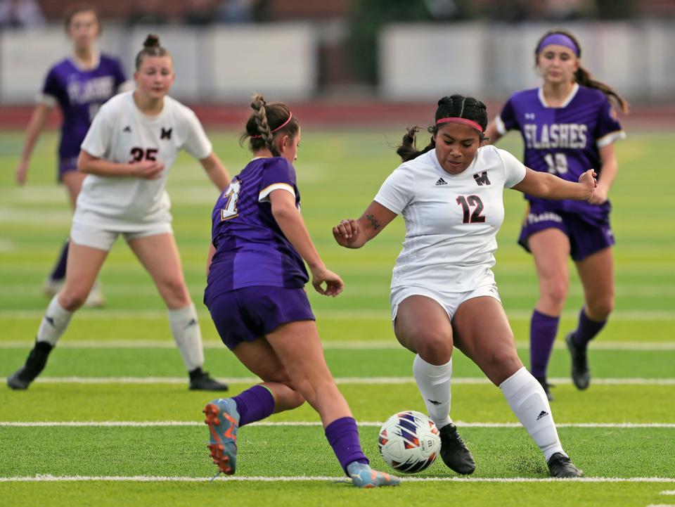 Manchester's Gina Tipton, right, takes the ball down the field against Champion's Maylee Nadaud during the second half of a Division III regional final Saturday in Tallmadge.