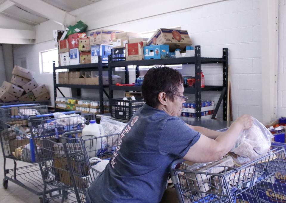Leticia Garcia, rural initiatives supervisor for Casa de Peregrinos emergency food pantry, stacks groceries in baskets on April 3, 2024, to prepare them for distribution to residents in Hatch, New Mexico.