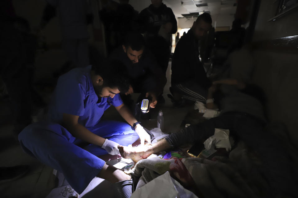 Palestinian medics treat a wounded person using torchlights after running out of power at the Indonesian hospital in Beit Lahiya during the ongoing bombardment of the northern Gaza Strip, Sunday, Nov. 19, 2023. (AP Photo/Ahmed Alarini)