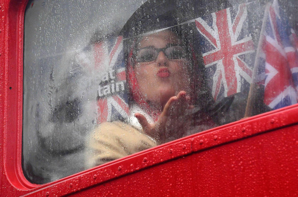 A woman gestures through a bus window as she attends the annual Goodwood Revival historic motor racing festival, celebrating a mid-twentieth century heyday of the racing circuit, near Chichester in south England