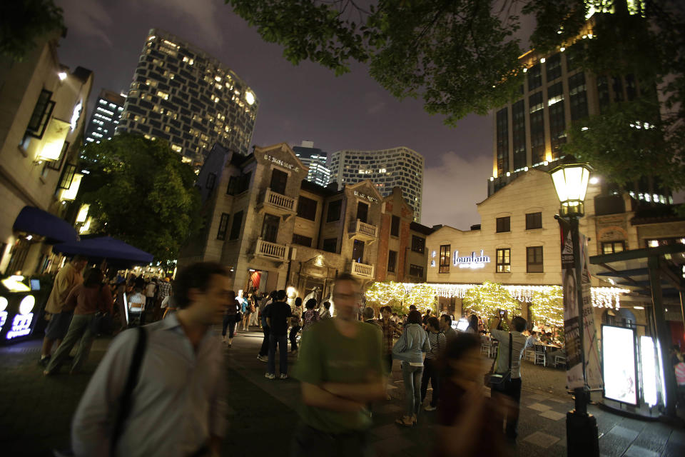 In this June 3, 2012 photo, people walk through Xintiandi, one of the most famous tourist destinations in Shanghai, China. Xintiandi, a complex of boutiques and restaurants, is a product of Deng’s market-style reforms launched in the 1980s to revive an economy nearly destroyed by three decades of Soviet-style central planning. (AP Photo/Eugene Hoshiko)