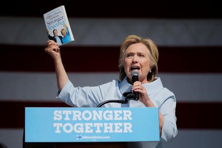 U.S. Democratic presidential candidate Hillary Clinton holds up the upcoming book from Clinton and her vice-presidential candidate Tim Kaine during a campaign stop at the 11th Congressional District Labor Day Parade and Festival in Cleveland, Ohio, United States September 5, 2016. REUTERS/Brian Snyder