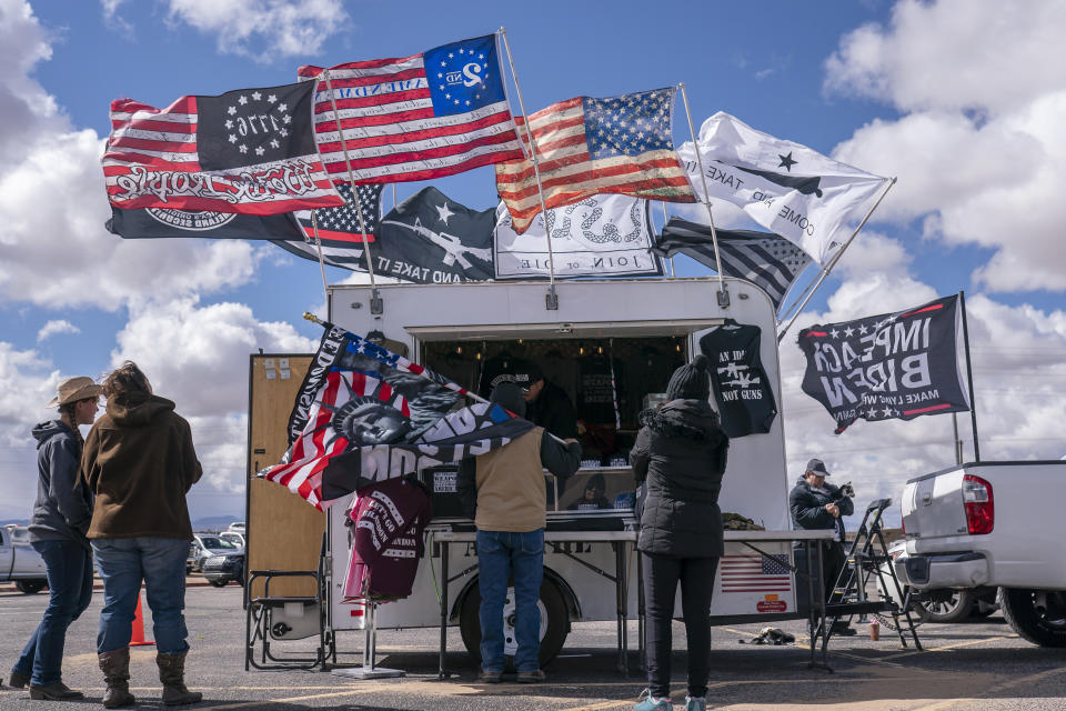 Supporters buy merchandise at the beginning of a trucker caravan to Washington, D.C., called The People's Convoy Wednesday, Feb. 23, 2022, in Adelanto, Calif. A small convoy of truckers demanding an end to coronavirus mandates began a cross-country drive from California to the Washington, D.C., area on Wednesday. (AP Photo/Nathan Howard)