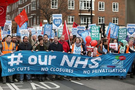 FILE PHOTO: People taking part in a demonstration to demand more funding for Britain's National Health Service (NHS) hold a banner, in London, March 4, 2017. REUTERS/Neil Hall