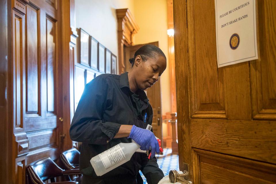 Custodian Brenda Love cleans the door handles at the Georgia State Capitol building during the 29th day of the Georgia Legislative session, Friday, March 13, 2020, in Atlanta.