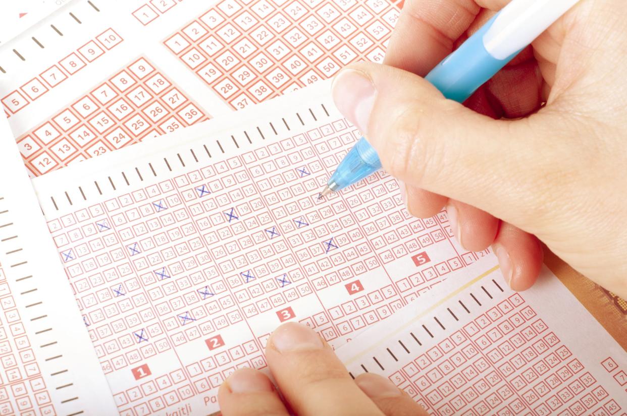 Person's Hand Marking Number On Lottery Ticket With Pen