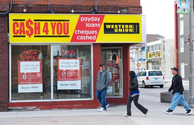 People walk pass a payday loan store in Oshawa Ont. on Saturday May 13, 2017. (Doug Ives/The Canadian Press - image credit)