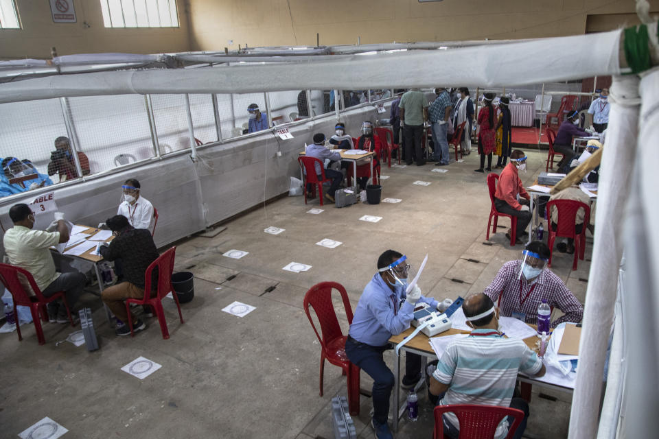 Election officials sit wearing masks and face shields during the counting of votes of Assam state assembly election in Gauhati, India, Sunday, May 2, 2021. With Indian hospitals struggling to secure a steady supply of oxygen, and more COVID-19 patients dying amid the shortages, a court in New Delhi said it would start punishing government officials for failing to deliver the life-saving items. (AP Photo/Anupam Nath)