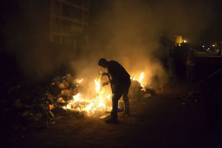 A man burns rubbish on the side of a road in Dandora, Nairobi, Kenya, June 14, 2015. REUTERS/Siegfried Modola