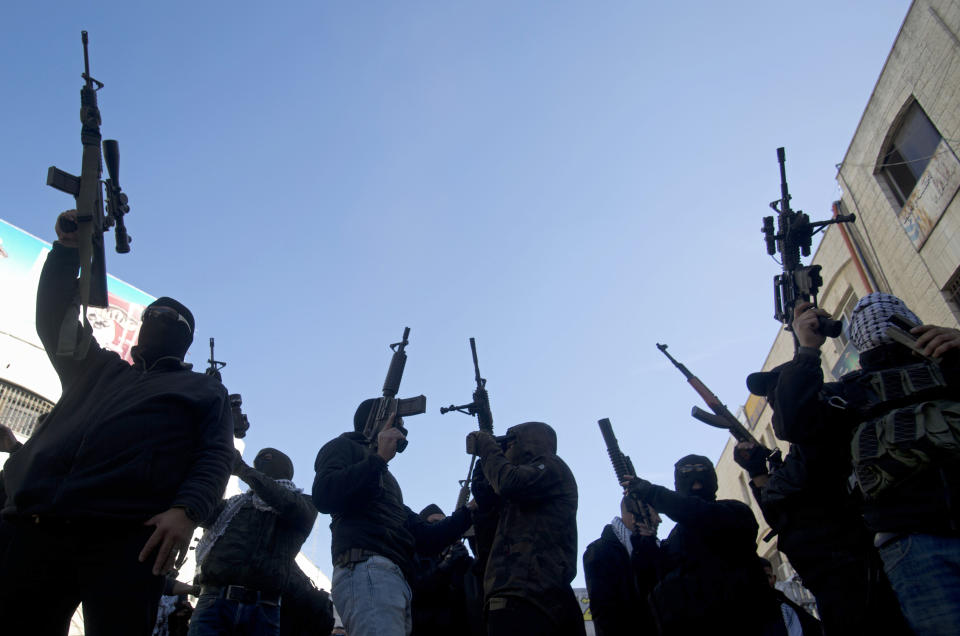 Masked Palestinians shoot in the air during a celebration marking the 55th anniversary of the Fatah movement in the West Bank city of Ramallah, Tuesday, Dec. 31, 2019. (AP Photo/Majdi Mohammed)