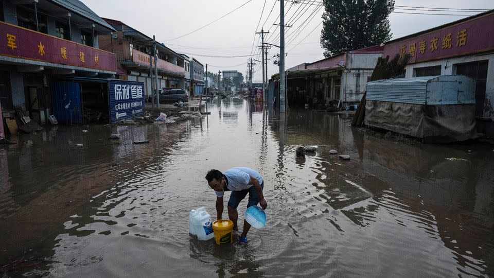 A man wades through receding floodwaters in a street in Zhuozhou on August 5. - Kevin Frayer/Getty Images