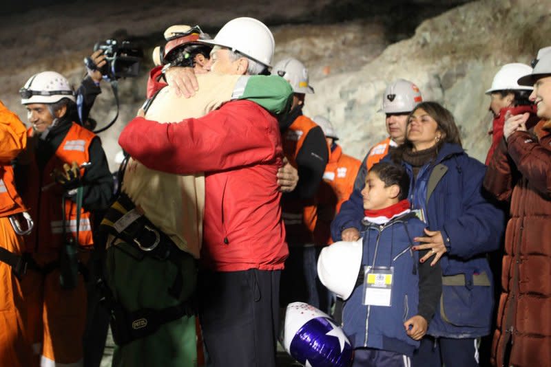 Chilean miner Florencio Avalos, the first of 33 trapped miners to be rescued, hugs President Sebastian Pinera and his son at the surface of the San Jose Mine near Copiapo, Chile, just after midnight October 13, 2010. Photo courtesy the Chilean government